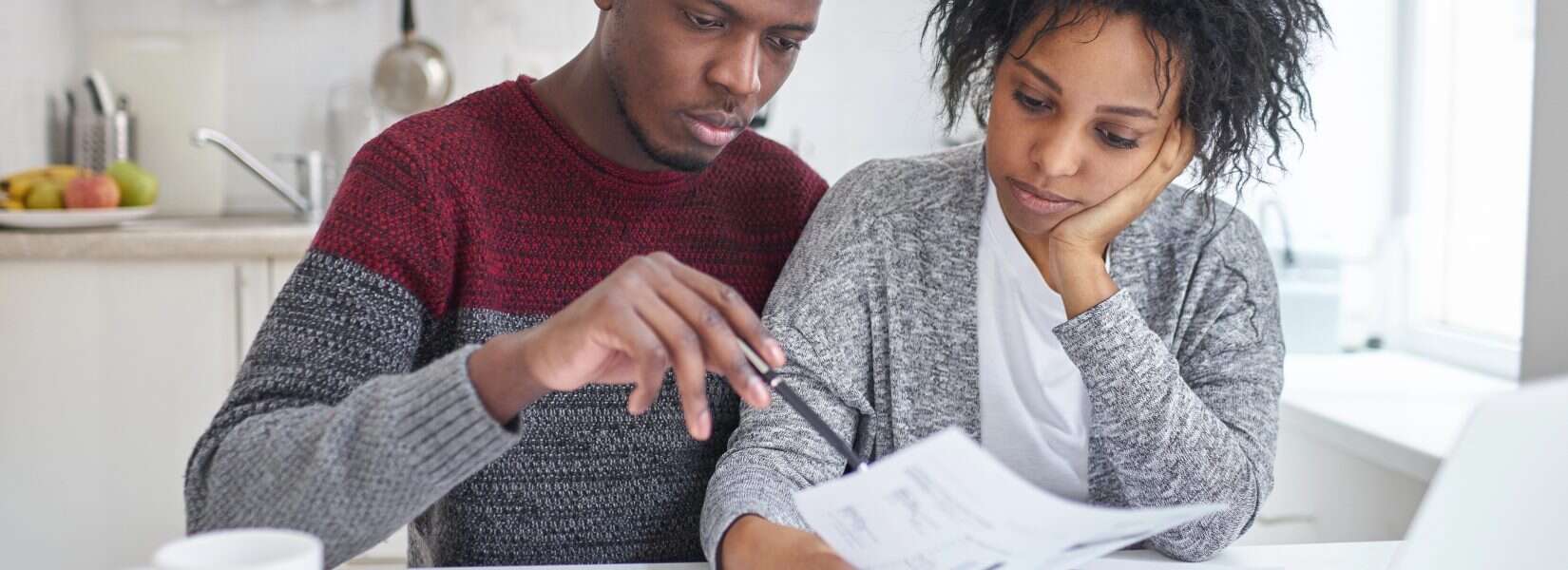 Budgeting your money - African American couple working on their budget on their kitchen table