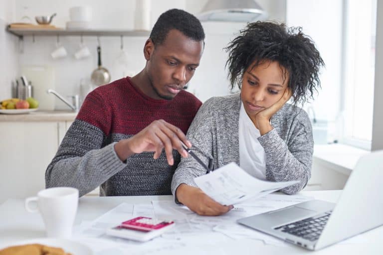 Budgeting your money - African American couple working on their budget on their kitchen table