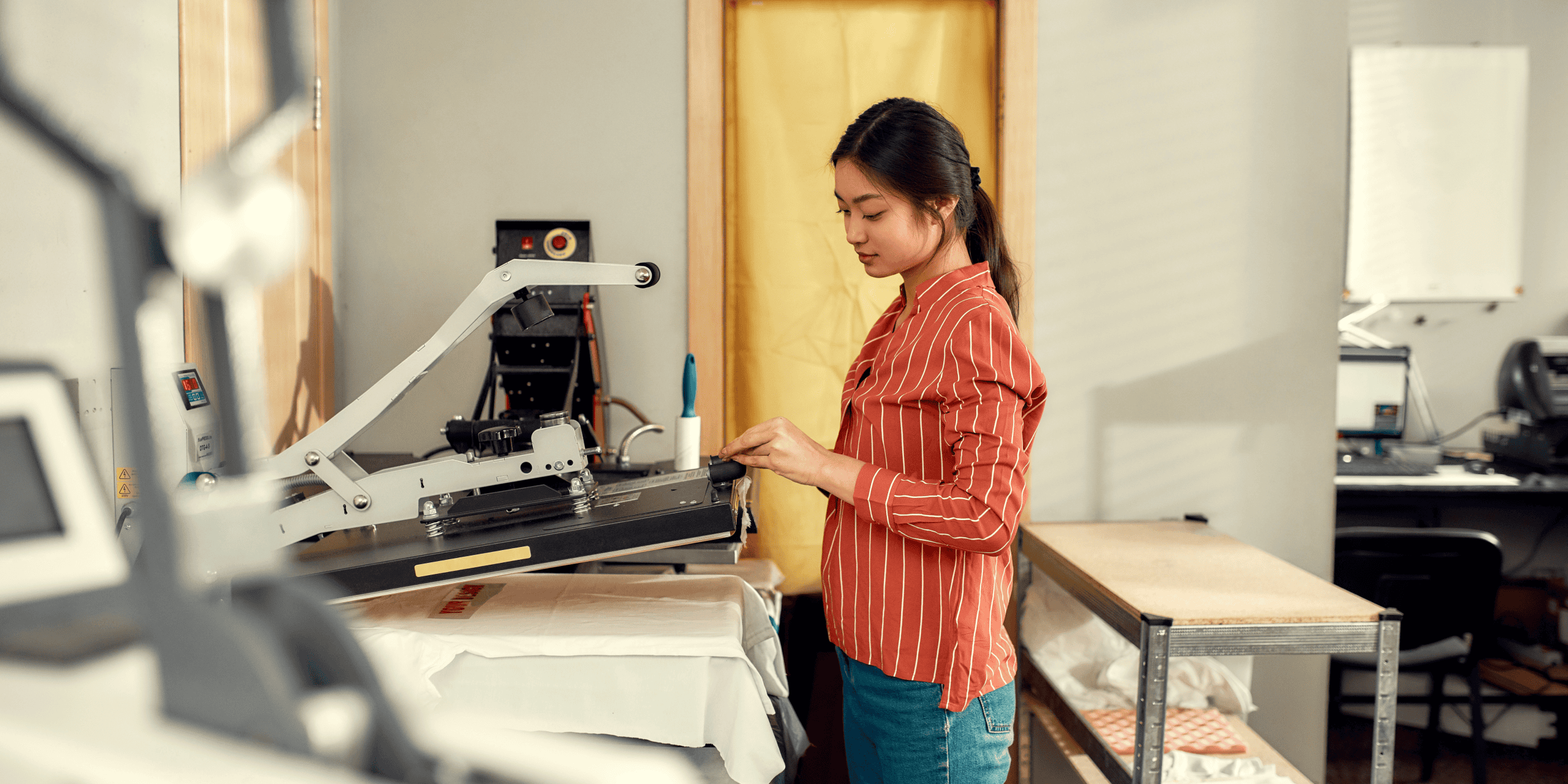 woman standing by a commercial Heat press making t shirts