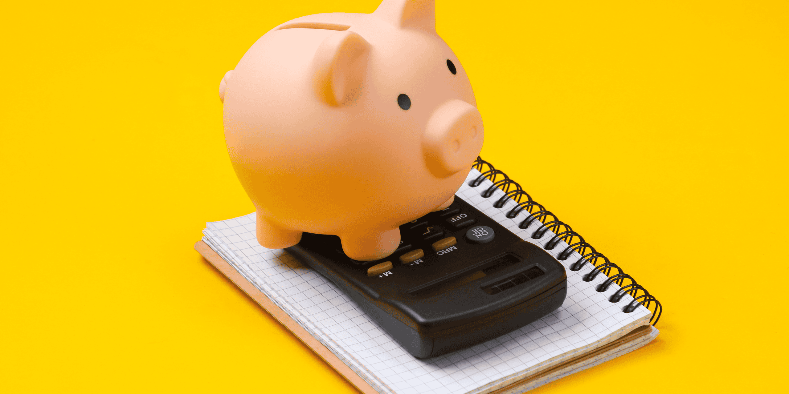 Teen Budgeting Tips - a piggy bank on a desk with calculator and notebook 