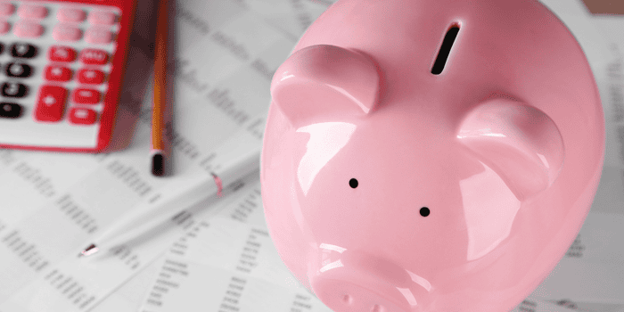Pink Piggy Bank with budgeting sheets, a calculator on the desk - teen banking basics