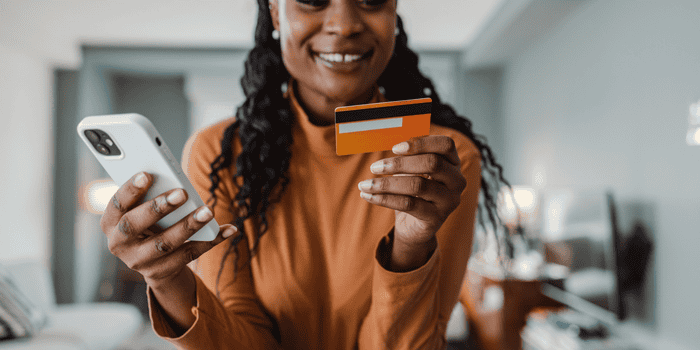 A young teen holding a credit card with her phone in her hand - teen banking basics