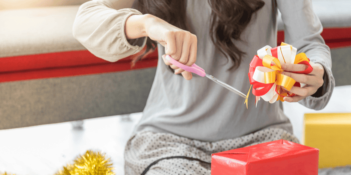 Teen sitting wrapping gifts - Holiday Gifts for Money Skills 