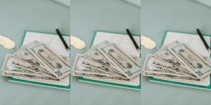 small journal laid out on desk with pen and US cash on top - Financial Journals for High Schoolers
