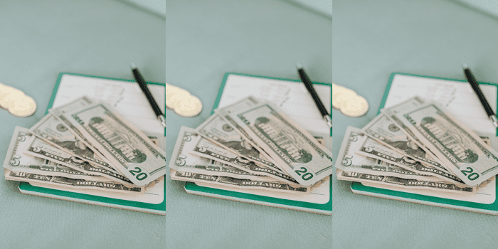 small journal laid out on desk with pen and US cash on top - Financial Journals for High Schoolers