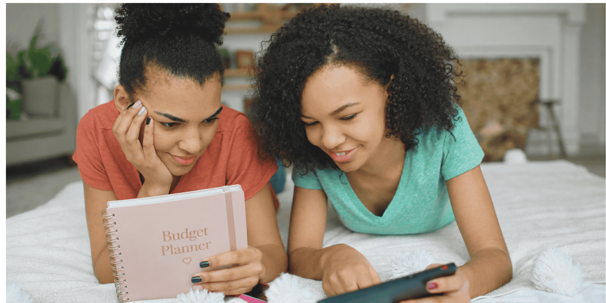 two young teens looking over teen budget planner and phone - back to school budget supplies teen girls